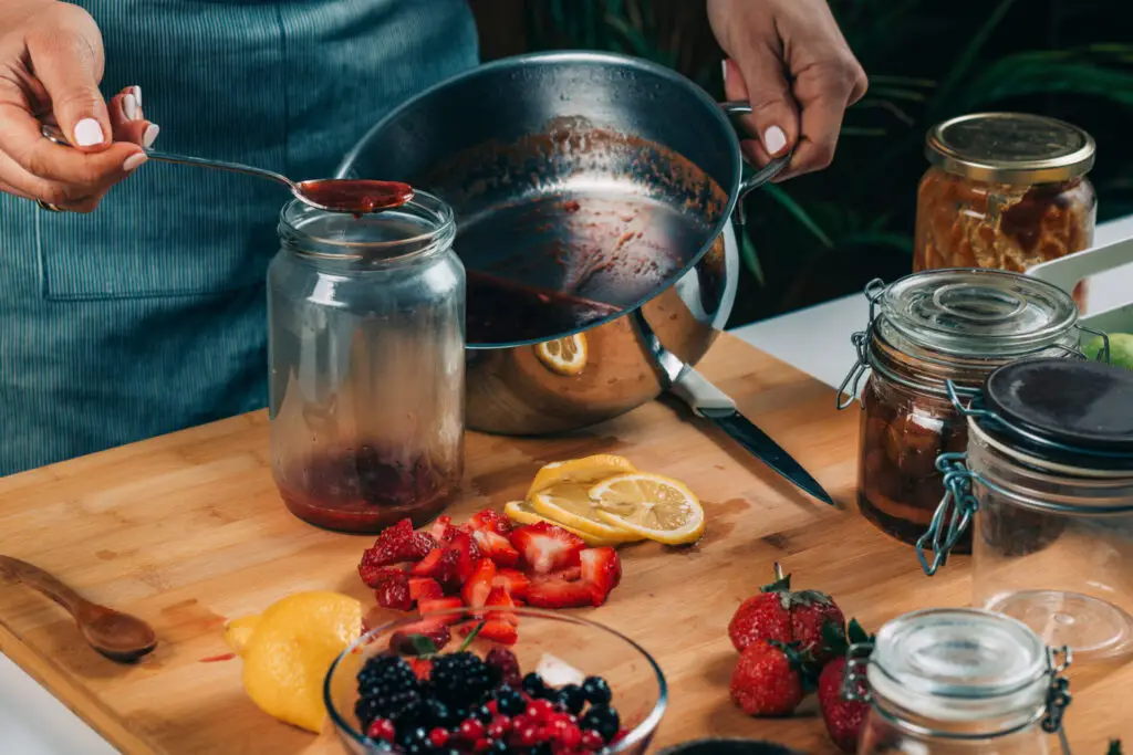 Homesteading In Small Spaces: Tips And Tricks 4 Pouring fruit jam into a jar, canning at home.