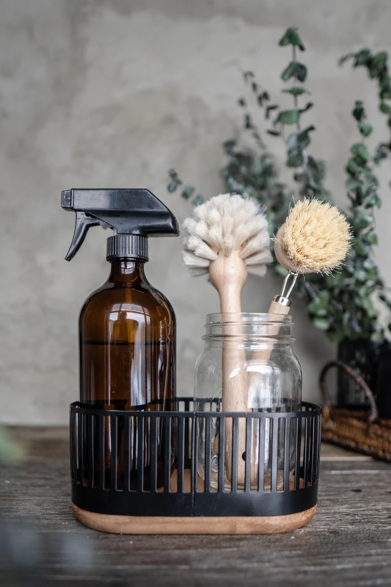 Aromatic cleaning supplies and brushes in a rustic holder.