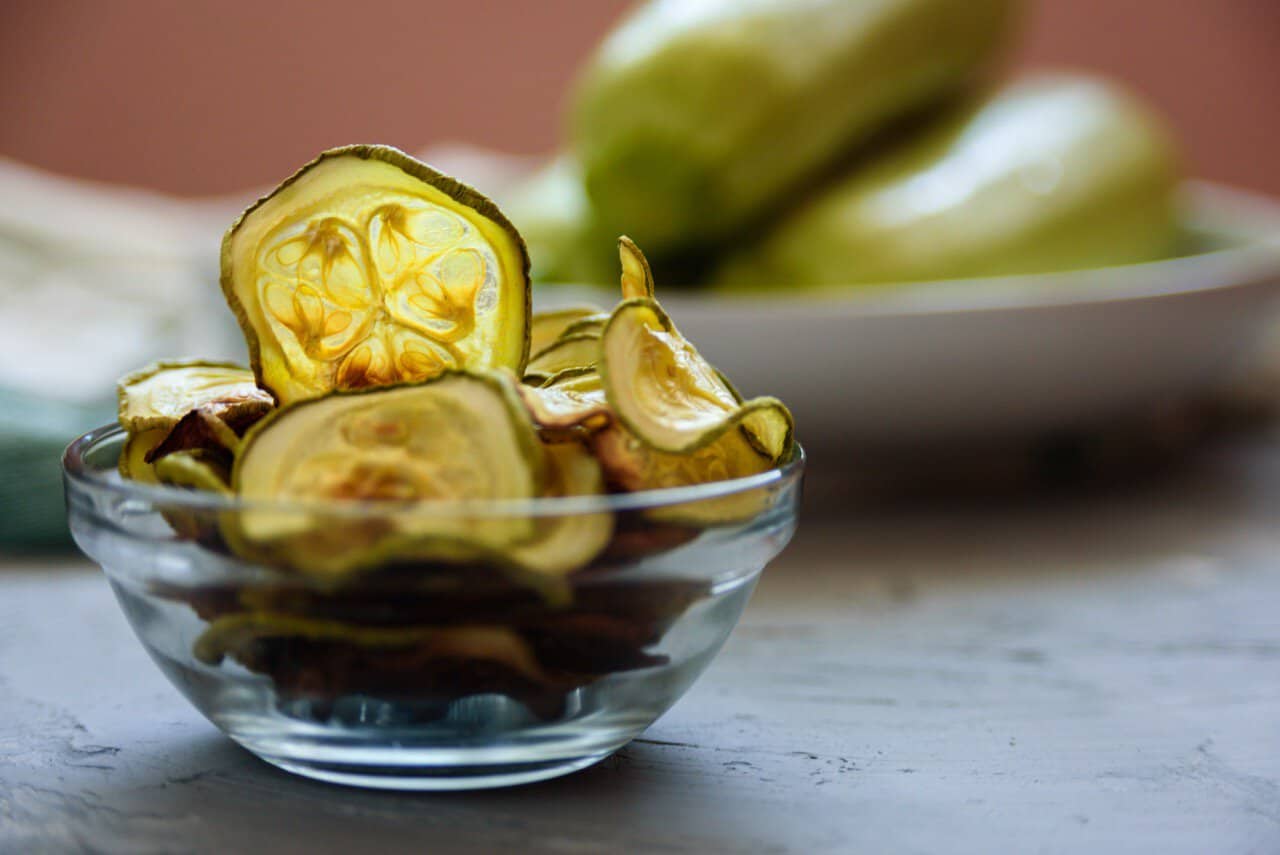 Crispy dehydrated zucchini chips in a glass bowl.