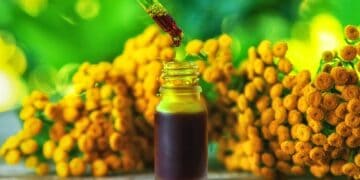 Homemade propolis tincture in a dropper bottle beside yellow flowers