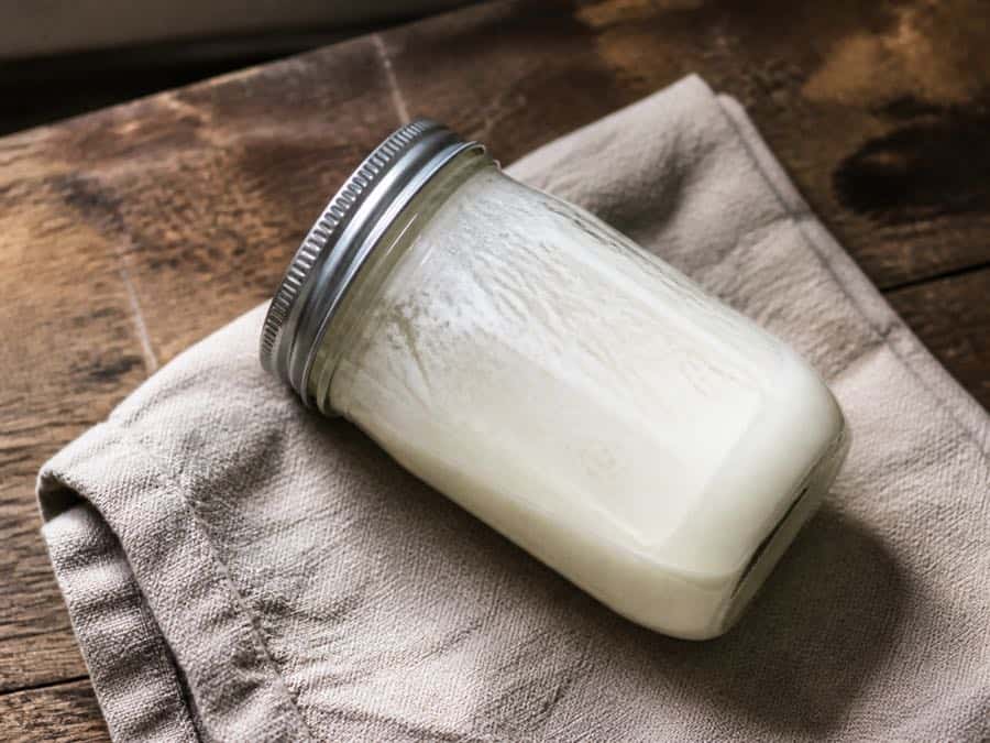 A tightly sealed jar after shaking, with cream streaks showing the agitation.