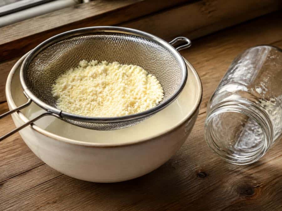 Butter granules draining in a fine mesh sieve with the buttermilk saved below.