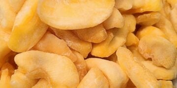 Close-up of frozen cashew nuts showing their creamy, pale yellow color and curved shape.