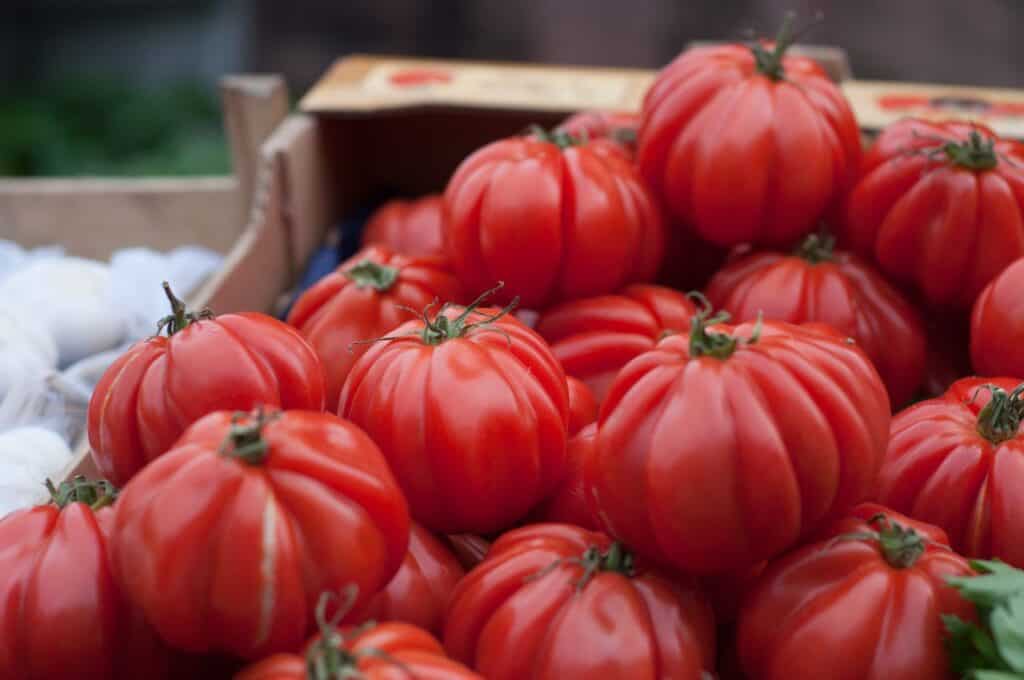 How To Can Tomatoes: A Beginner'S Guide 1 A close-up of vibrant red heirloom tomatoes on display at a market stand. How to can tomatoes